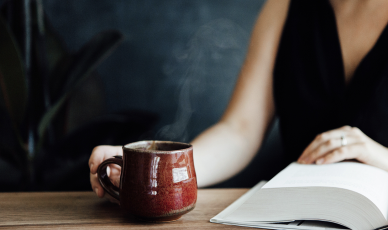 someone reading a book while enjoying a cup of coffee